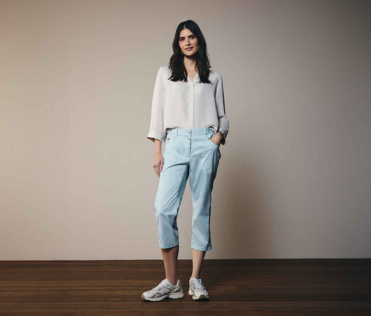 Femme portant une chemise claire et un pantalon 3/4 Cecil «
New York
» bleu clair. Elle porte des baskets.