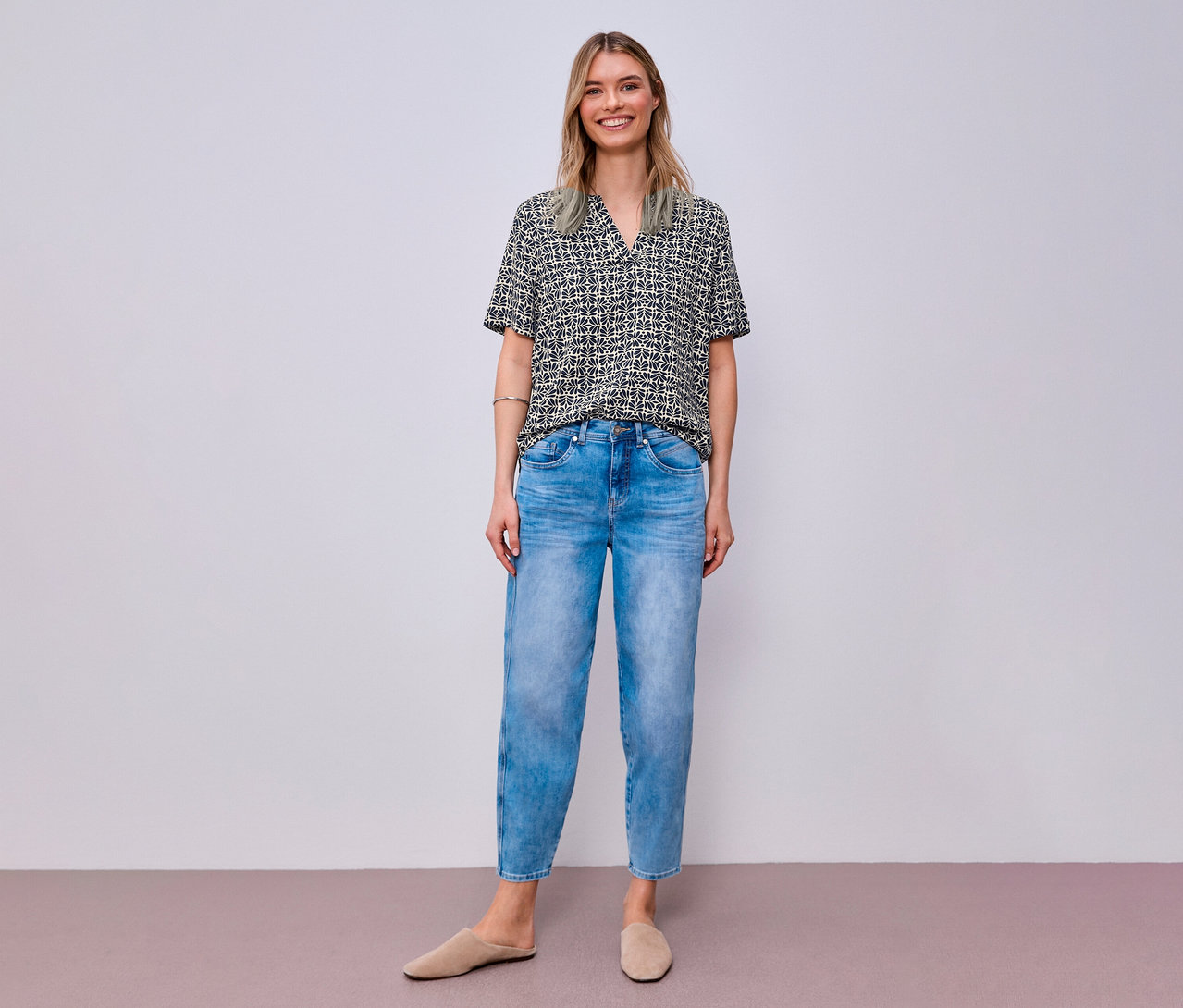 Femme souriante portant un jean et une blouse en maille Street One à motifs.