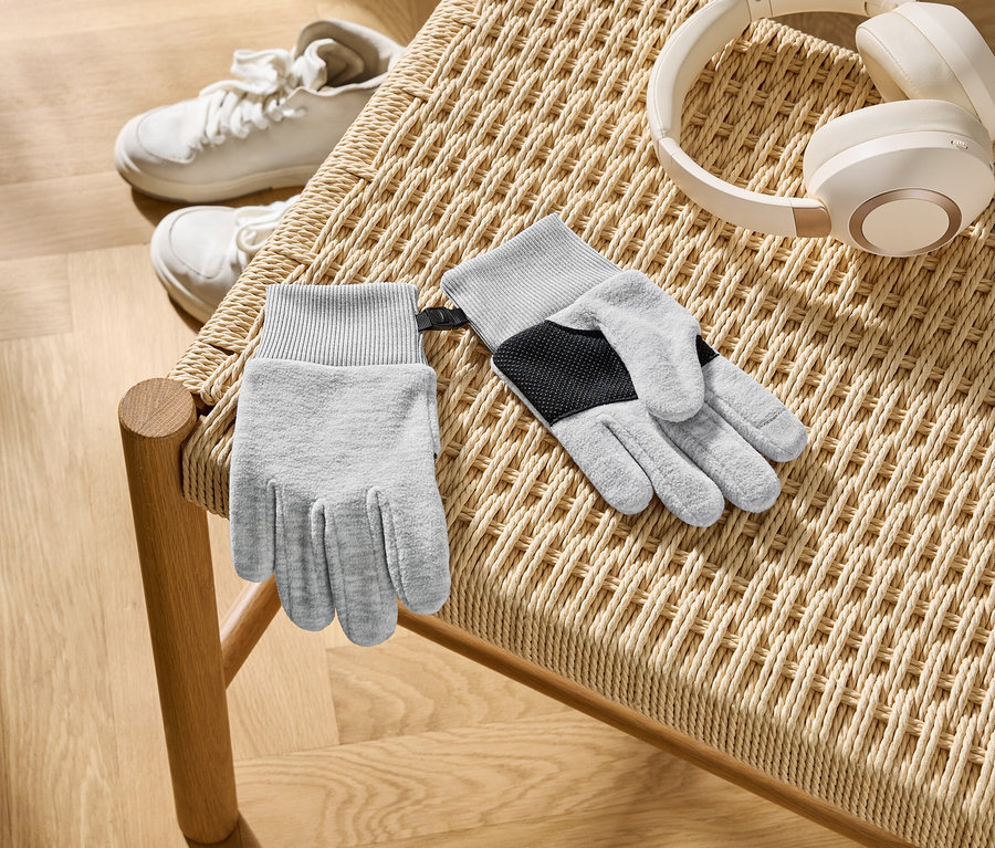 Sur une chaise tressée reposent des gants gris, un casque blanc et des baskets blanches.