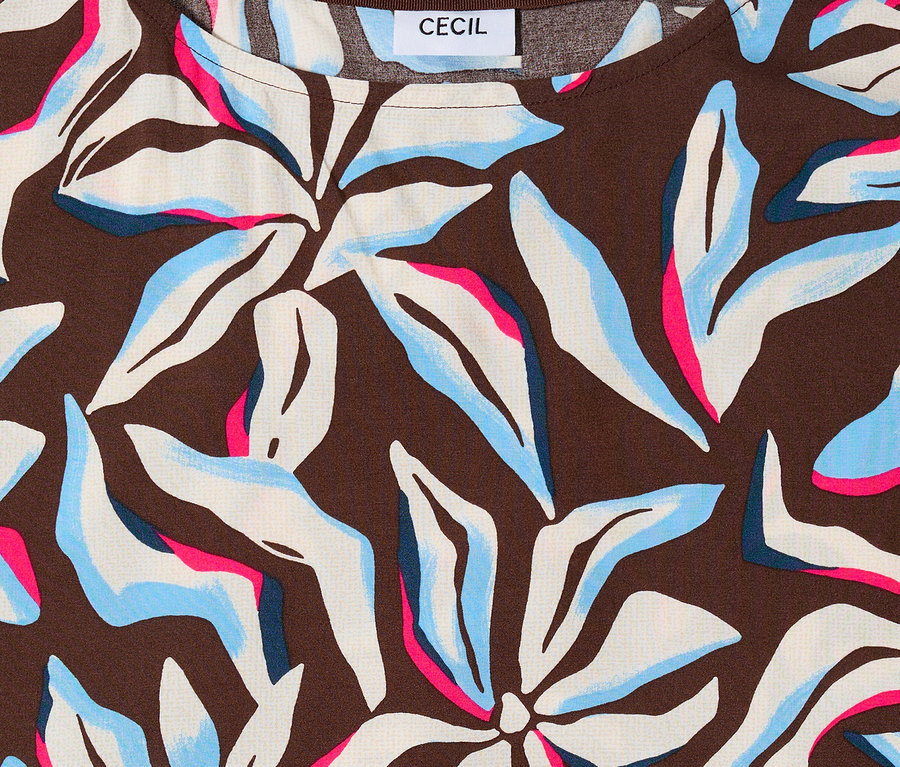 Gros plan sur le chemisier à manches courtes CECIL avec fond marron et motif floral bleu, blanc et rose.