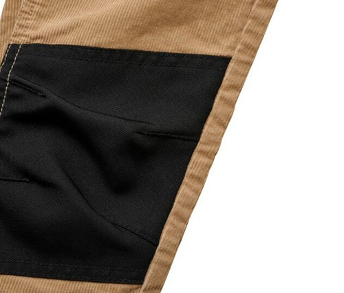 Gros plan d'un vêtement avec un empiècement en tissu noir cousu sur du tissu en velours côtelé beige, avec des coutures claires visibles.