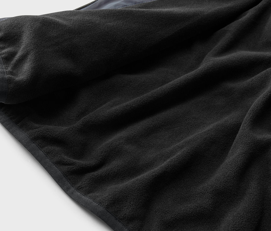 Gros plan d'une doublure polaire noire avec une bordure grise sur un fond gris clair.