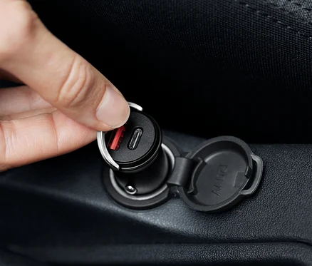 Une main branche un chargeur de voiture USB-C noir.