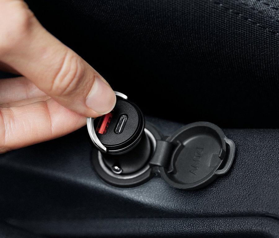 Une main branche un chargeur de voiture USB-C noir.