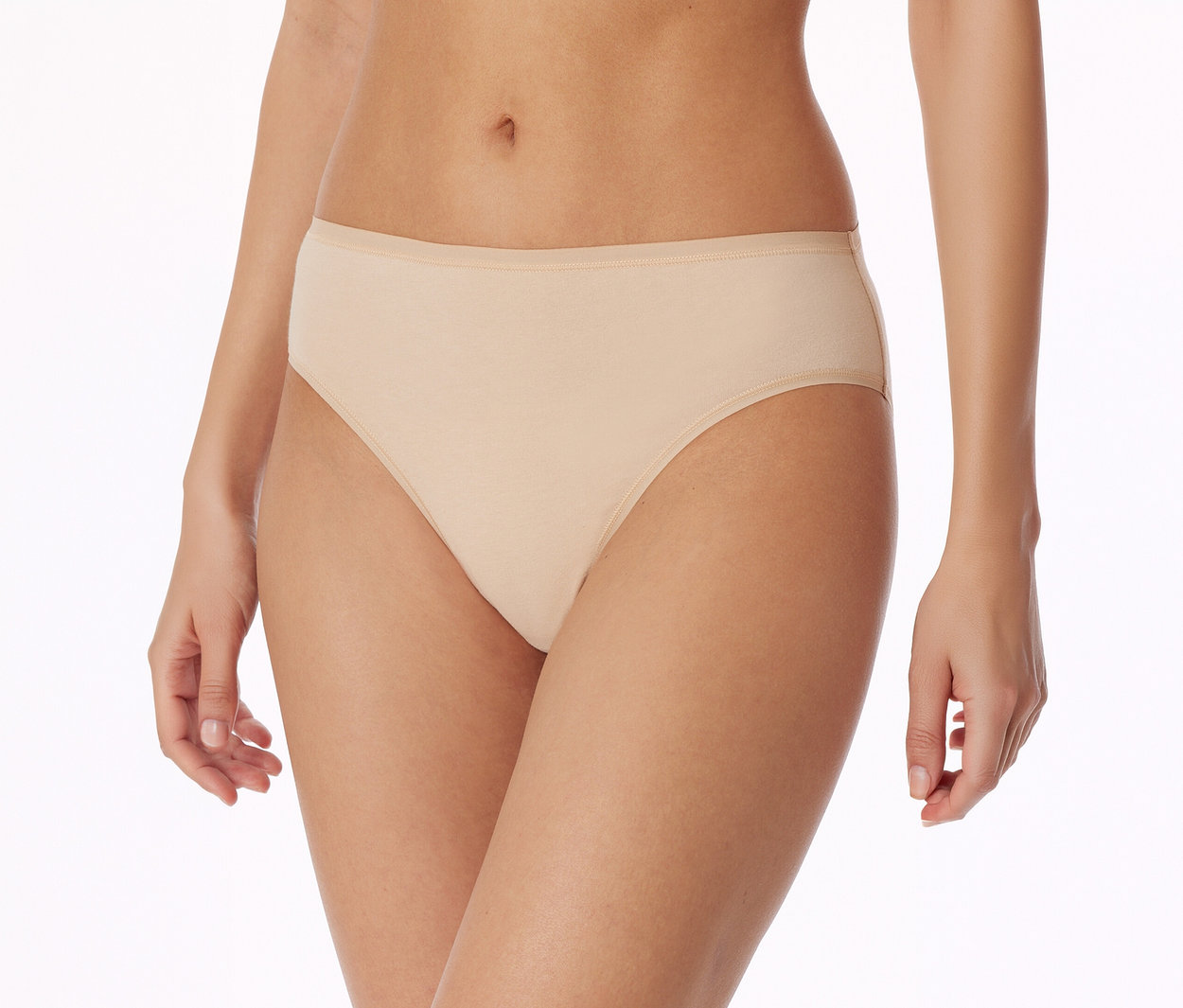 Gros plan d'une personne portant une culotte beige clair avec une fine ceinture élastique, debout sur un fond blanc.