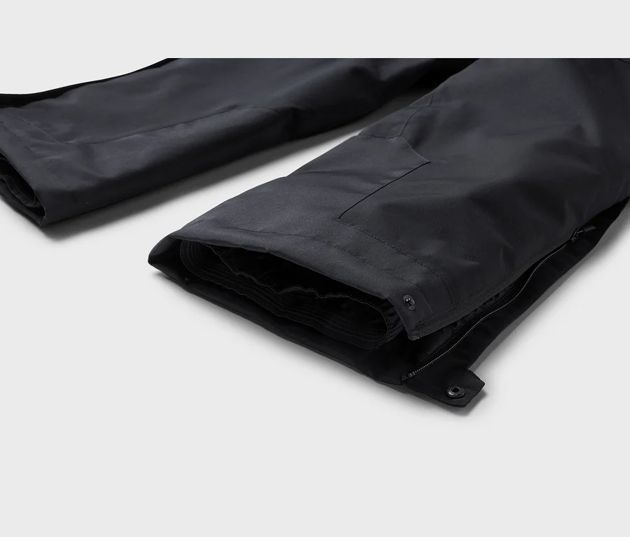 Deux jambes de pantalon noires, avec le bas de jambe ouvert doté de boutons-pression et d'une fermeture éclair au premier plan.