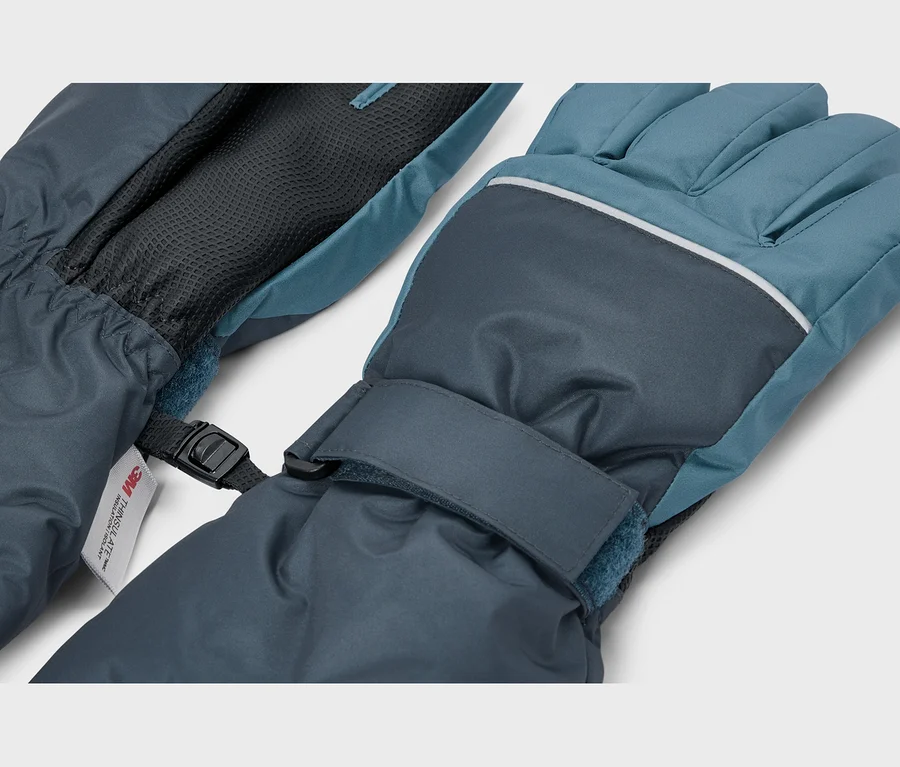 Une paire de gants d'hiver bleu foncé et turquoise, reliés par une boucle en plastique noire. Le gant droit présente une bande réfléchissante sur les jointures et une sangle velcro au poignet. Une étiquette "3M Thinsulate" est visible sur le gant gauche.
