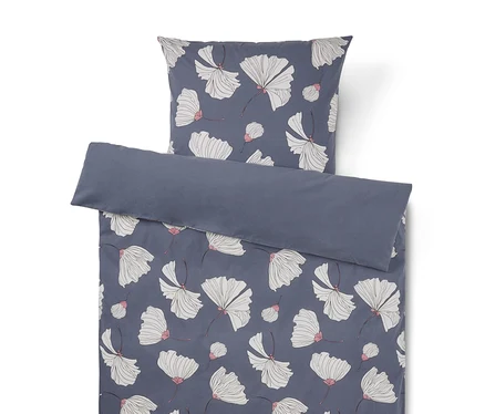 Parure de lit avec un fond bleu foncé et un motif de fleurs blanches aux accents roses. La taie d'oreiller est au-dessus de la housse de couette, dont le bord supérieur est replié pour révéler un revers uni bleu foncé.
