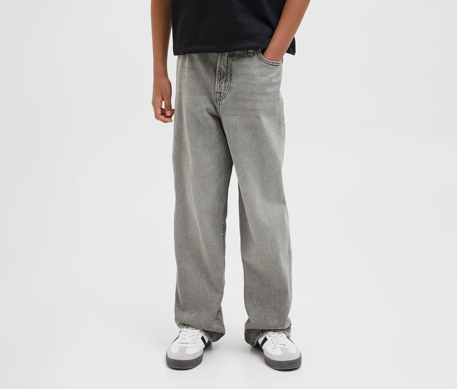 Une personne porte un jean gris Jack&Jones JJOriginal Alex et des baskets blanches. Une main est dans la poche.