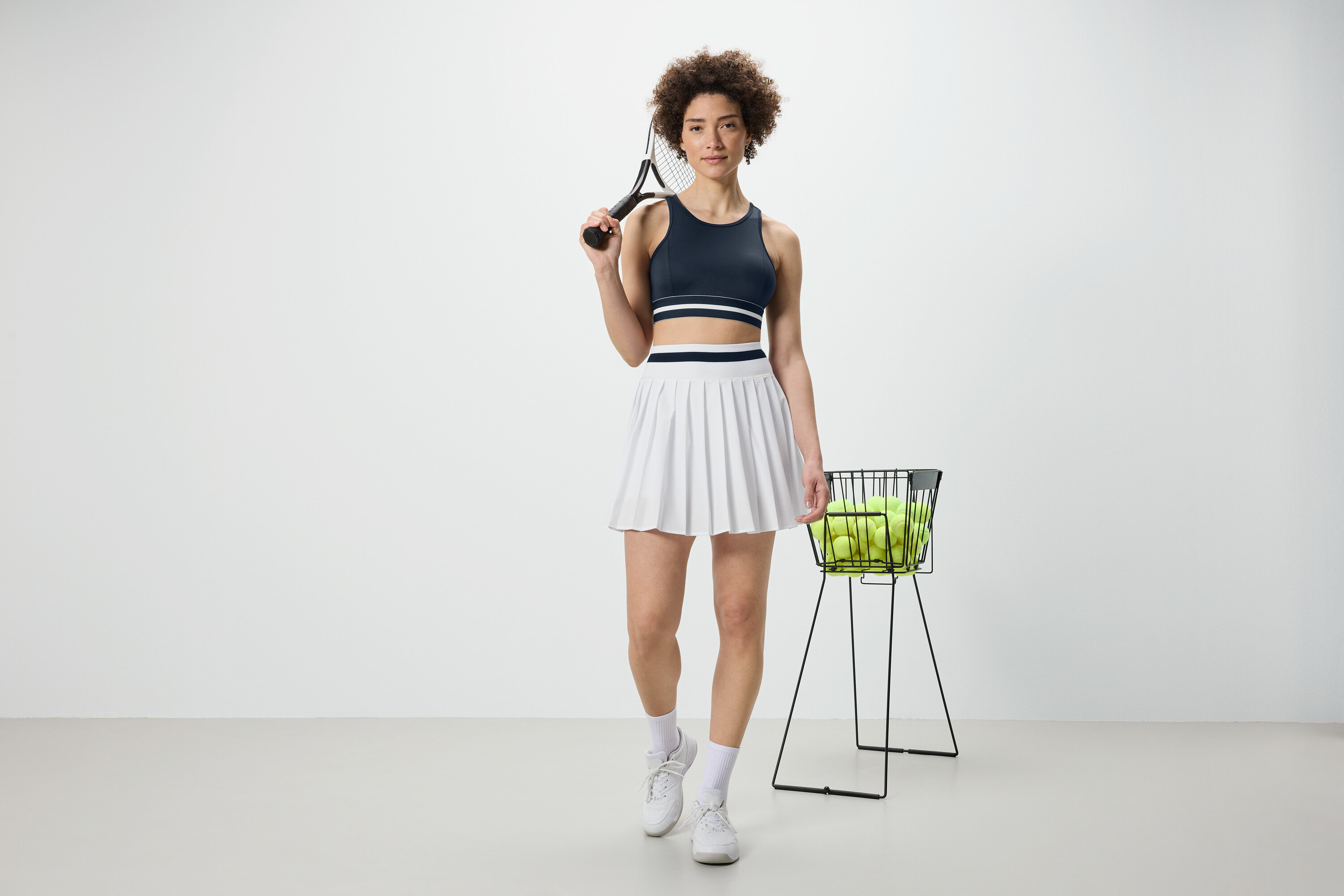 Femme tenant une raquette de tennis et portant un bustier de sport bleu « Crop Top ».