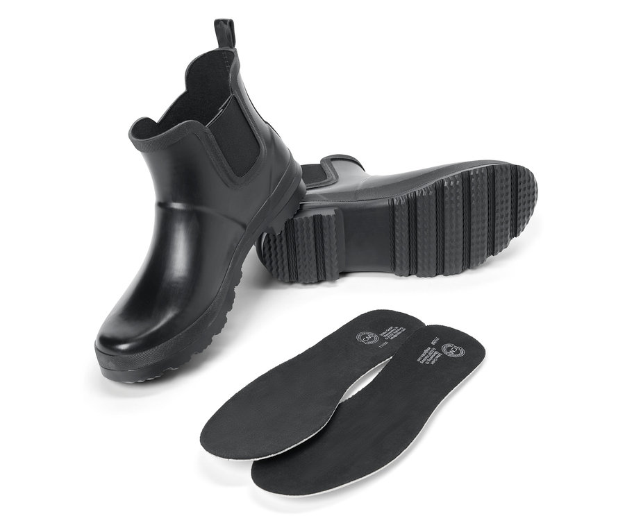 Deux bottes en caoutchouc noires et deux semelles intérieures noires sur fond blanc.