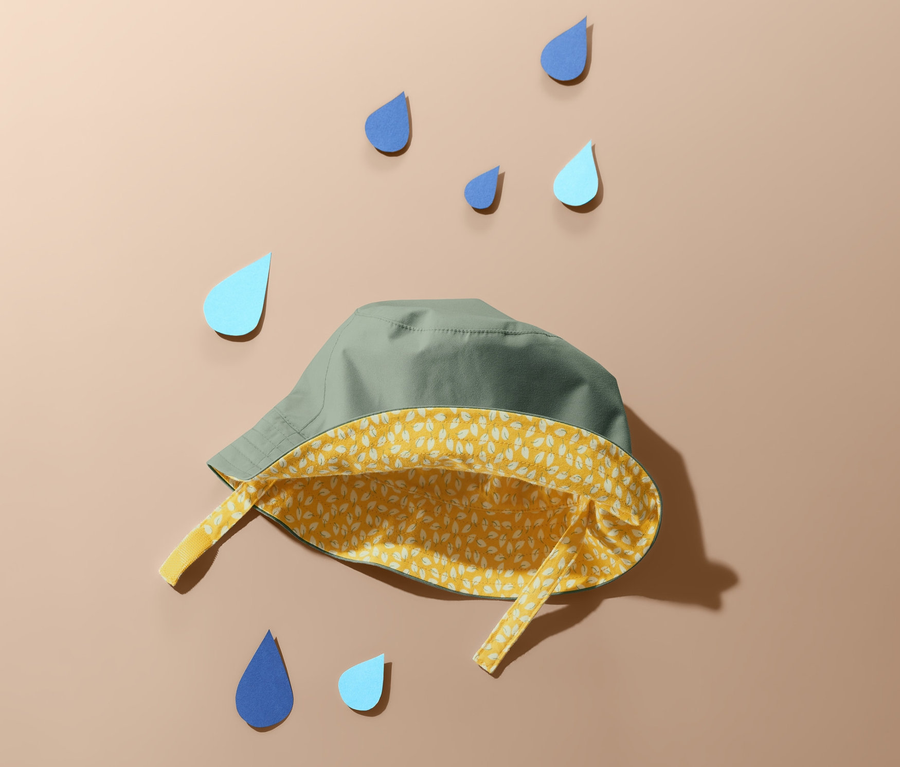 Un chapeau de pluie vert est posé sur un fond beige, entouré de gouttes de pluie bleues.