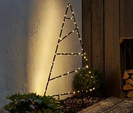 Un grand sapin d'extérieur à LED en métal se dresse à côté d'un mur en bois.
