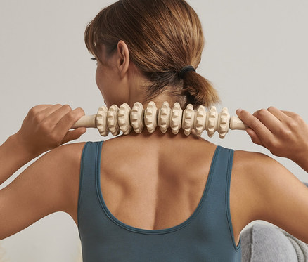 Femme utilisant un rouleau en bois pour fascias sur le cou.