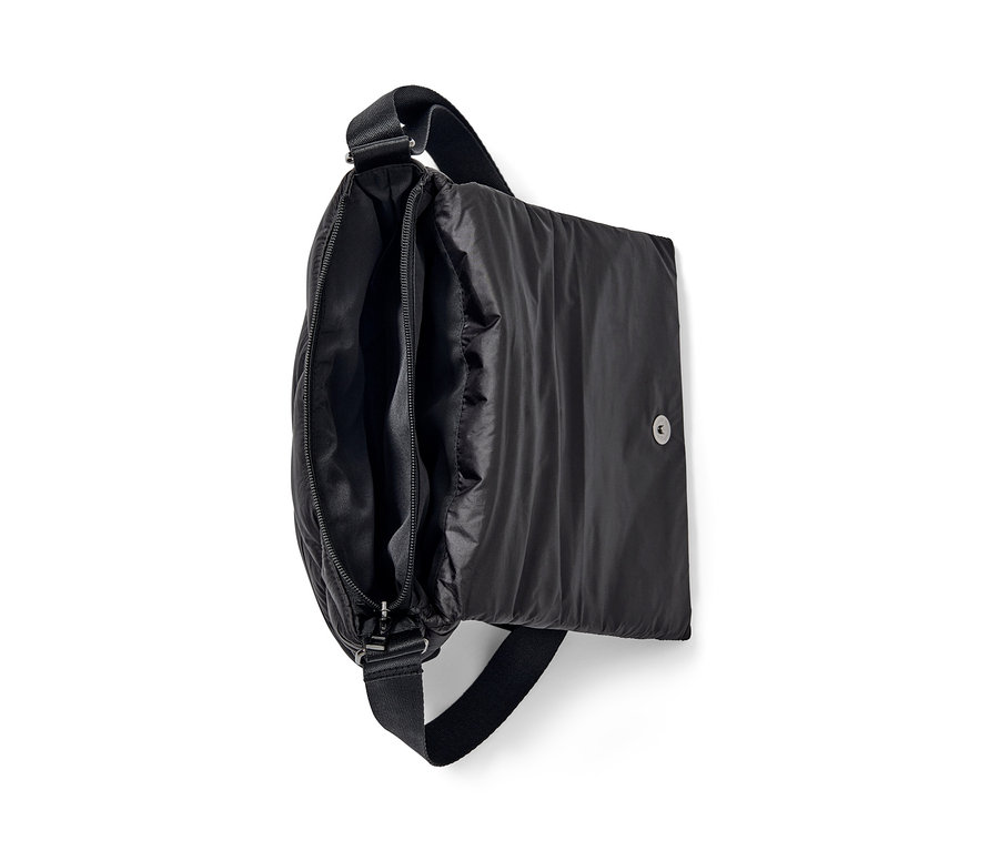 Un sac matelassé noir à bandoulière est ouvert, montrant le compartiment à fermeture éclair.