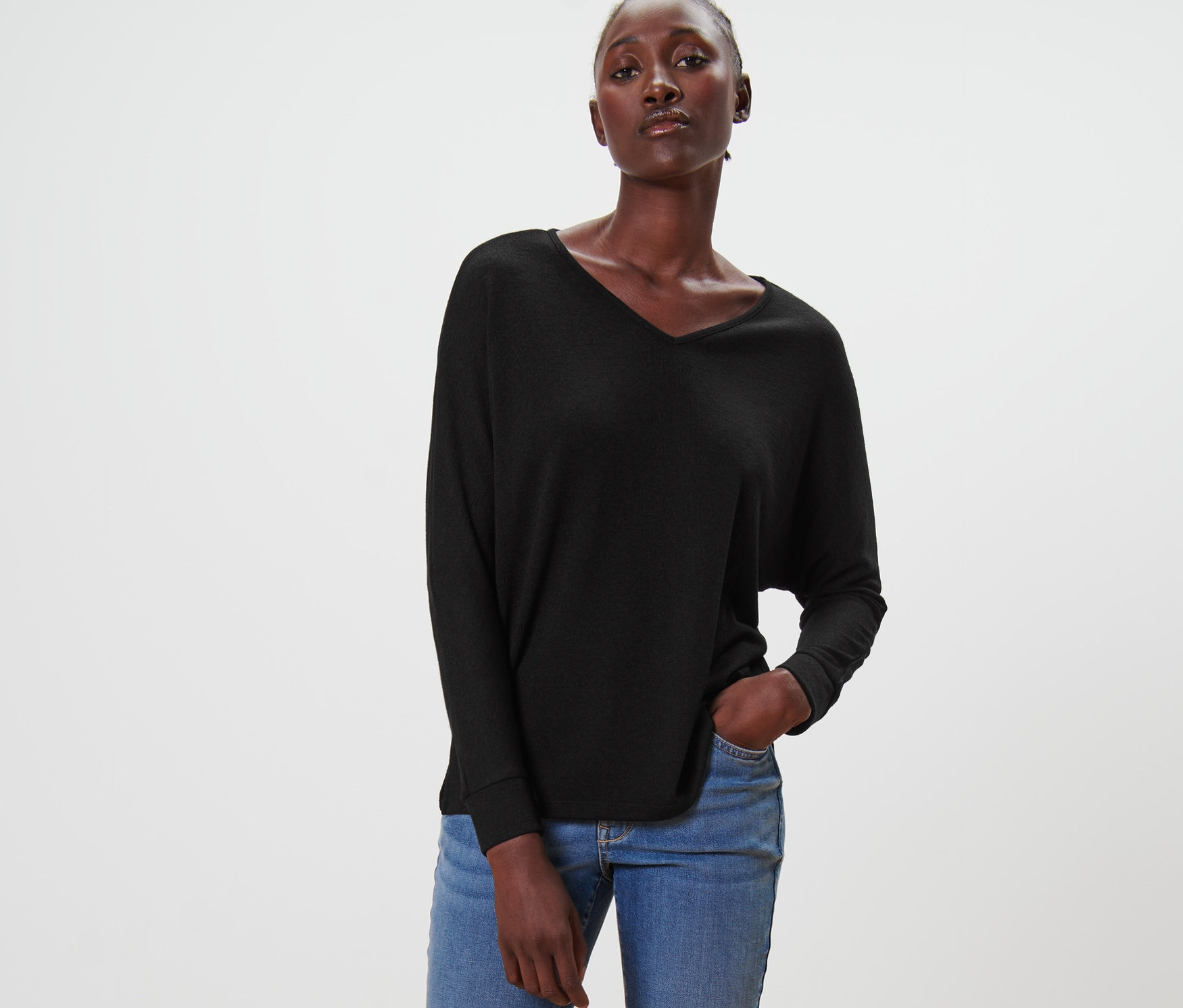 Femme posant en t-shirt manches chauve-souris noir, jean et mocassins.