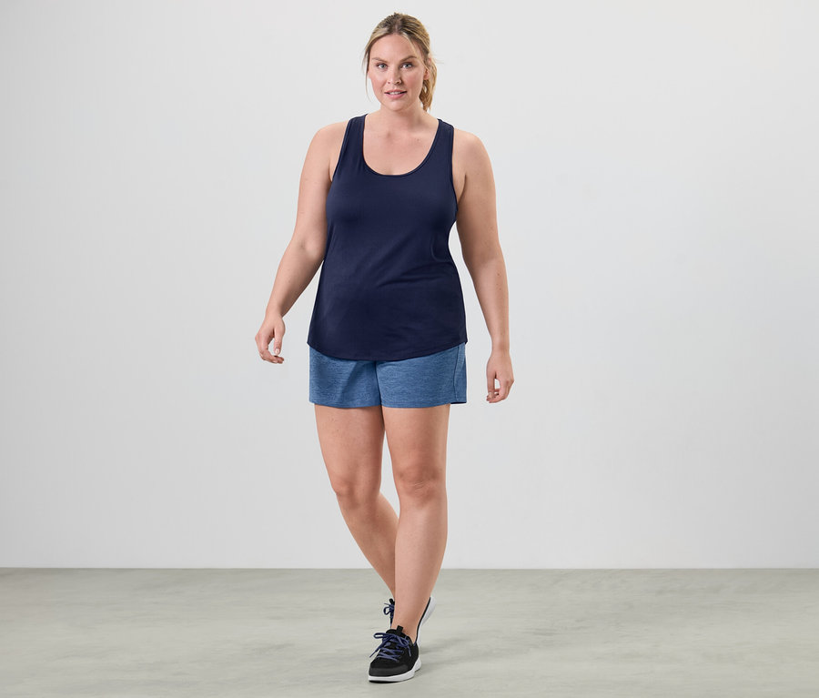 Une femme marche et porte un des 2 tops techniques, rose vif et bleu.