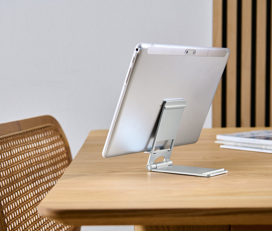 Tablette appuiée sur un support pour smartphone et tablette sur une table en bois.