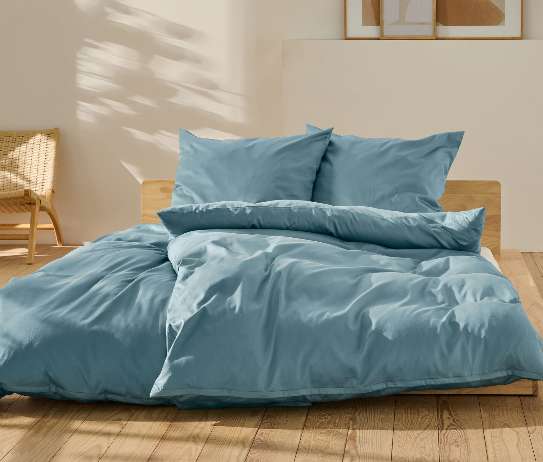 Parure de lit en satin de coton bleu, taille standard et grande taille, sur un lit.