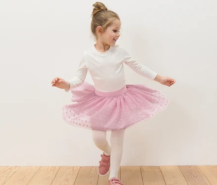 Fillette dansant en haut blanc et jupe en tulle rose pour enfant.