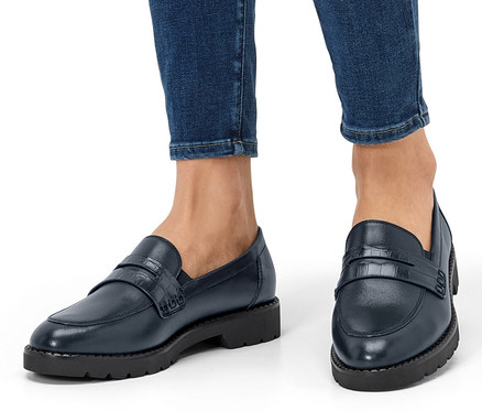 Jambes d'une personne en jean et mocassins en cuir.