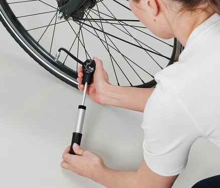 Femme gonflant un pneu de vélo avec une mini-pompe double course.