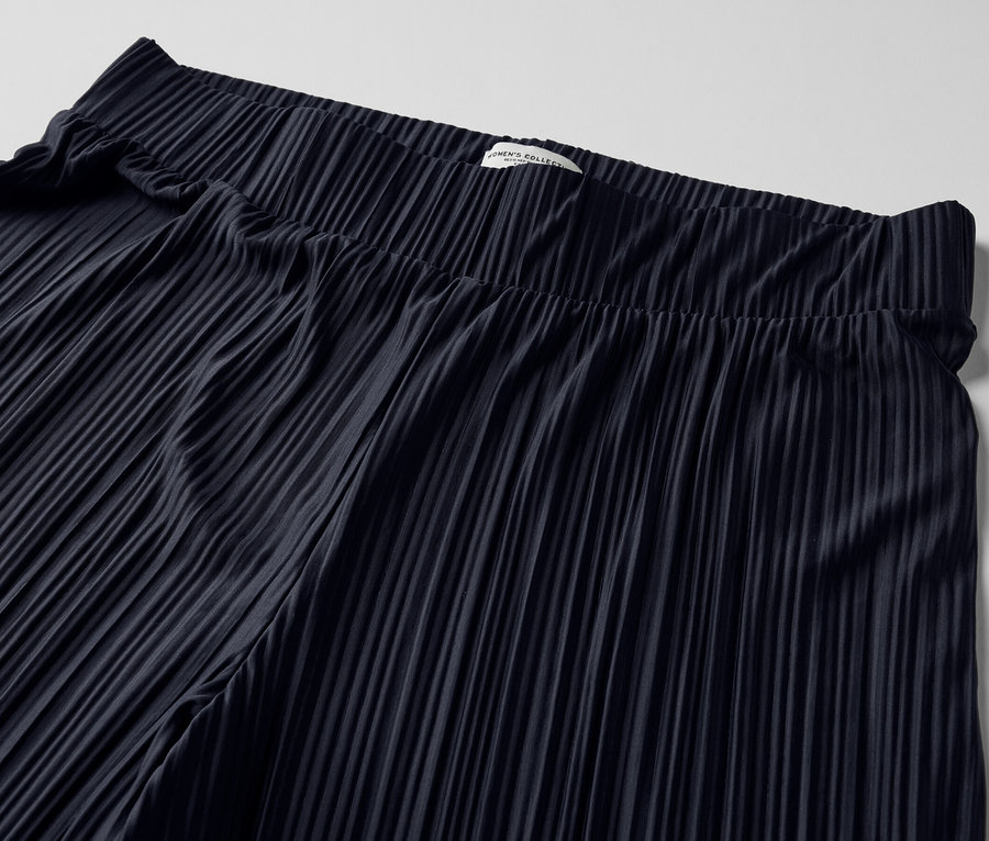 Gros plan d'un pantalon plissé bleu foncé.