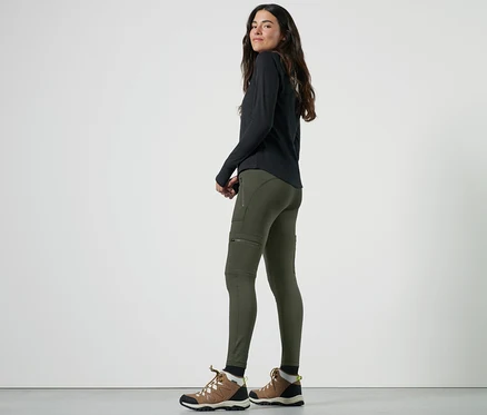 Femme posant en legging thermique outdoor et chaussures de randonnée.