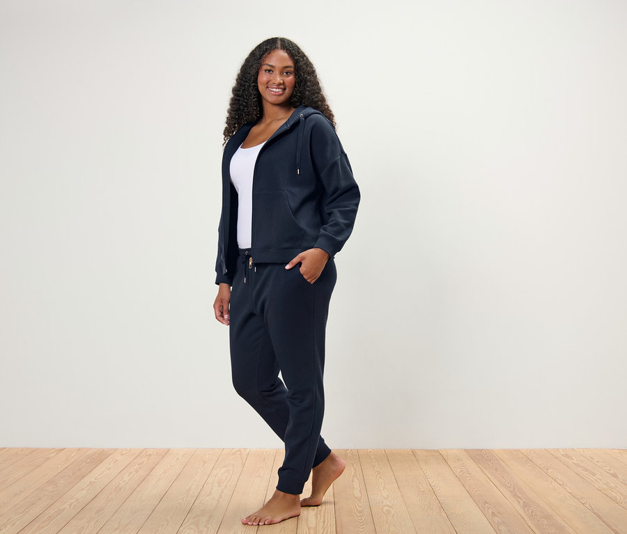 Femme debout posant dans un survêtement d’intérieur bleu marine.