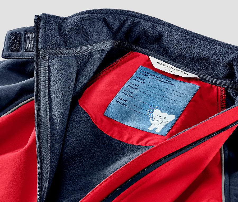Détail d'une combinaison en softshell pour enfant rouge et bleue.