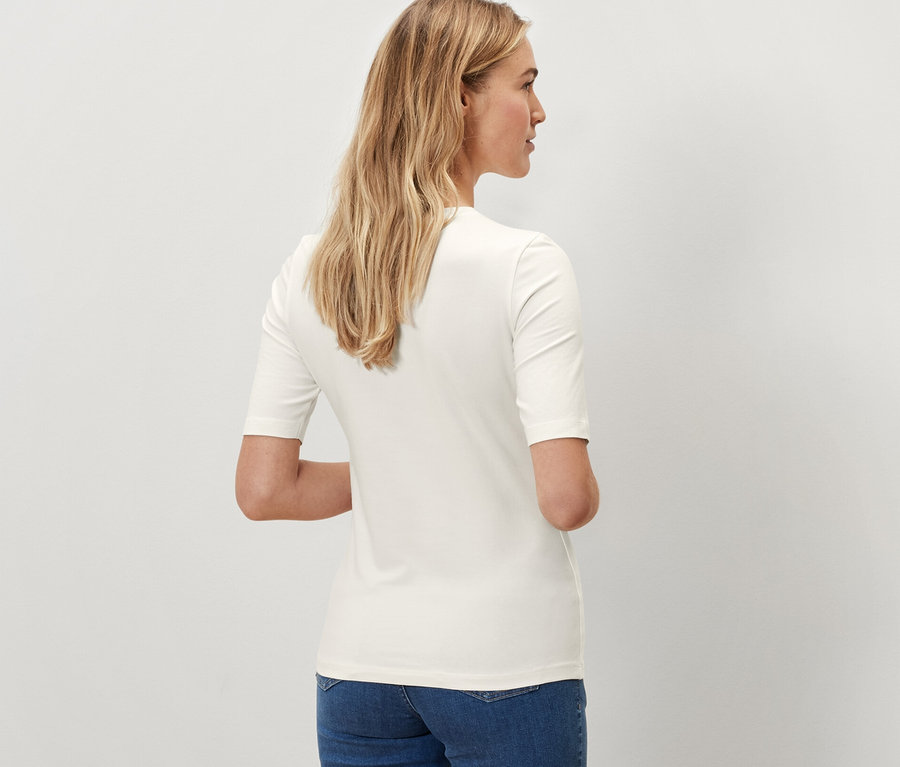 Vue arrière d'une femme portant un t-shirt demi-manches crème et un jean bleu.