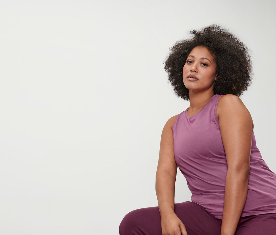Une femme portant un corsaire de yoga mauve et un haut de sport mauve.