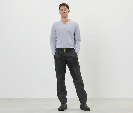 Un homme debout portant un pantalon de pluie noir.