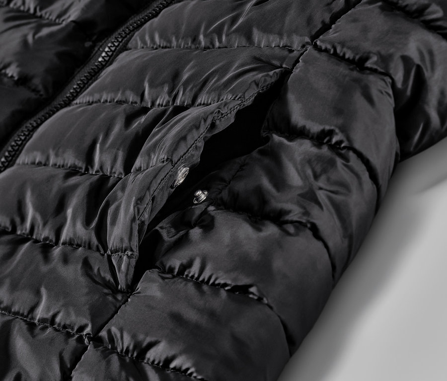 Détail d'un gilet noir matelassé avec poche.