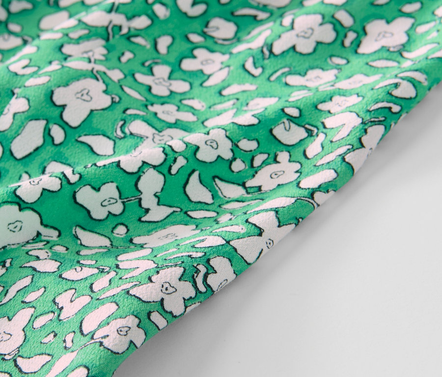 Gros plan sur une jupe midi imprimée verte.