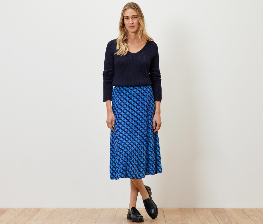 Femme posant dans un pull bleu marine et une jupe midi imprimée.