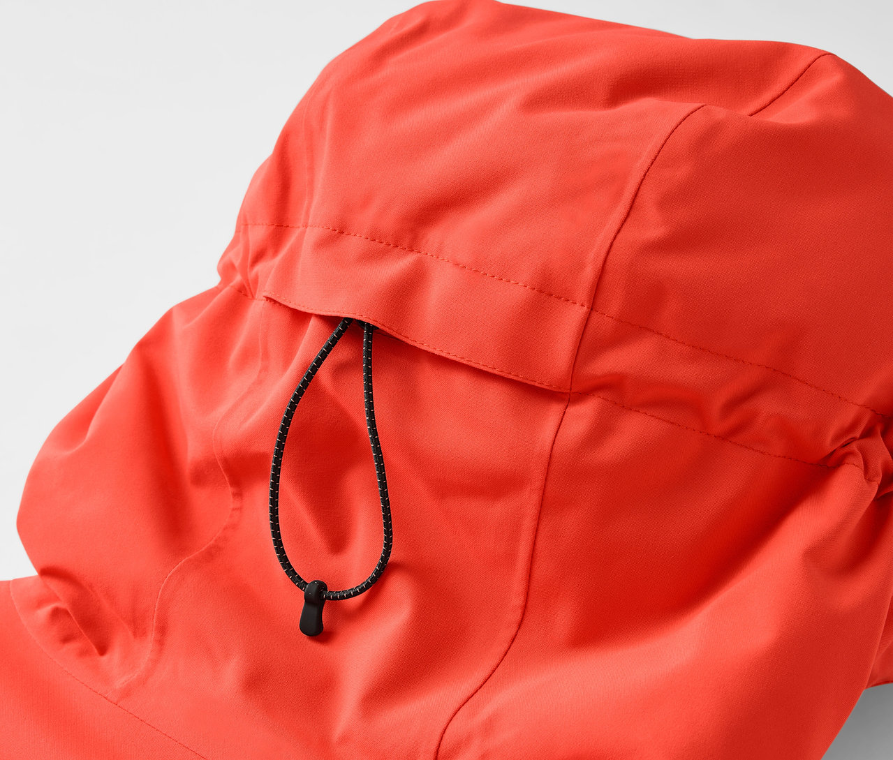 Gros plan sur la capuche d'une veste orange avec cordon de serrage.