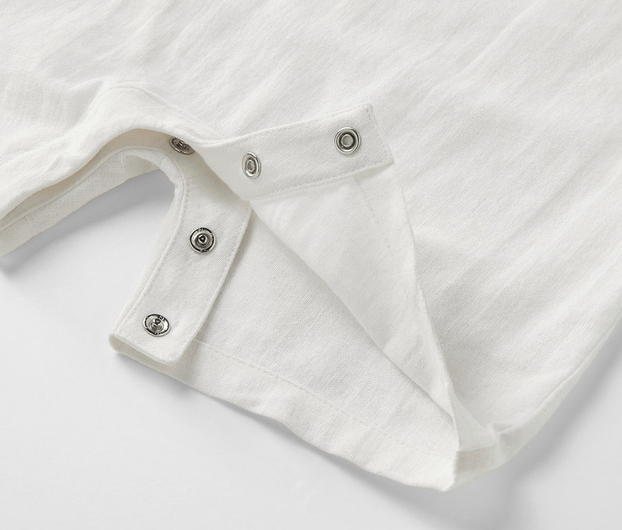 Gros plan sur une barboteuse de style marin blanche pour bébé avec boutons-pression.