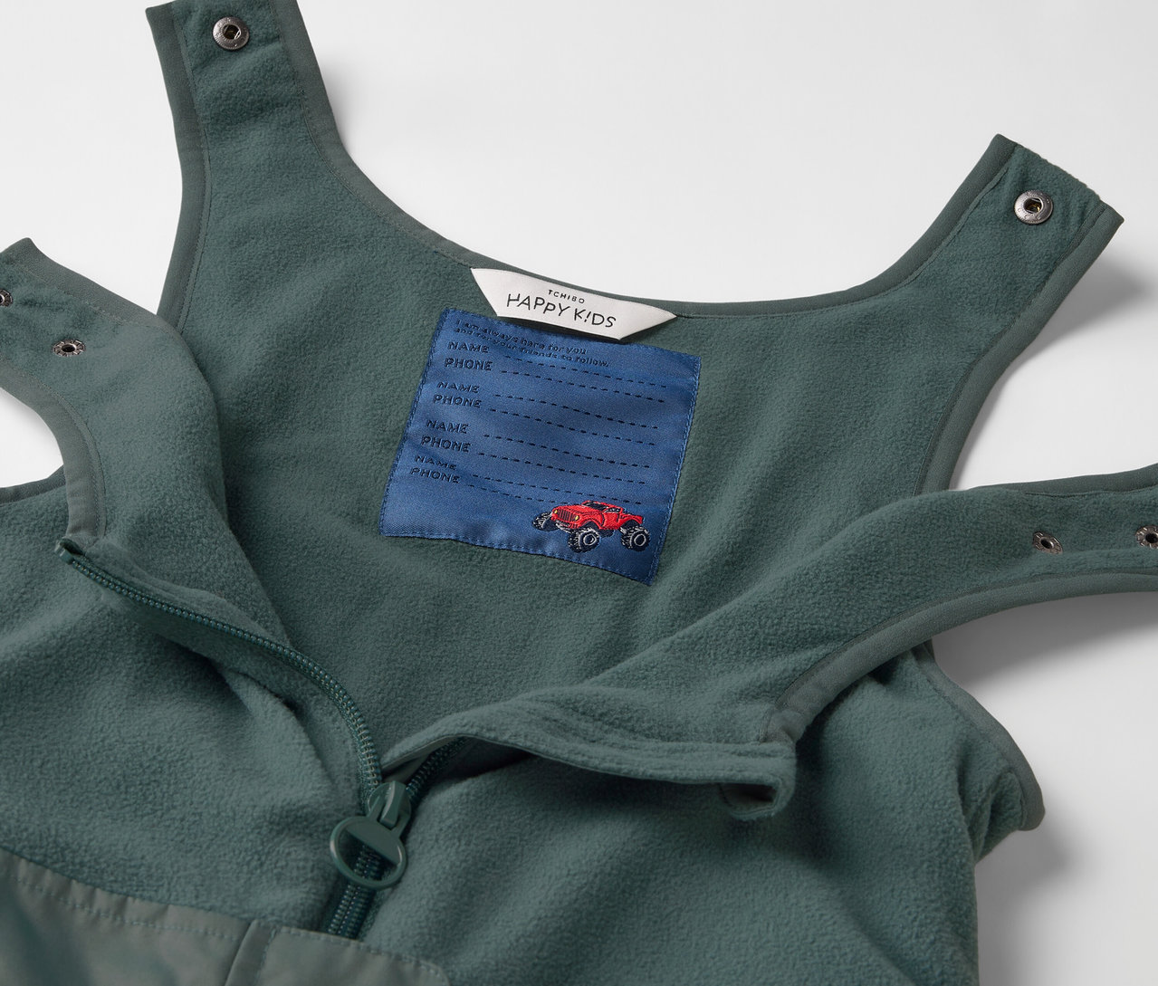 Détail d'un pantalon de pluie thermique pour enfant avec poche poitrine et voiture rouge.