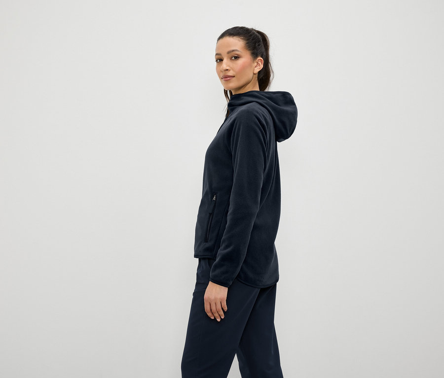 Femme portant un sweat à capuche en polaire bleu marine et un pantalon, debout de côté.