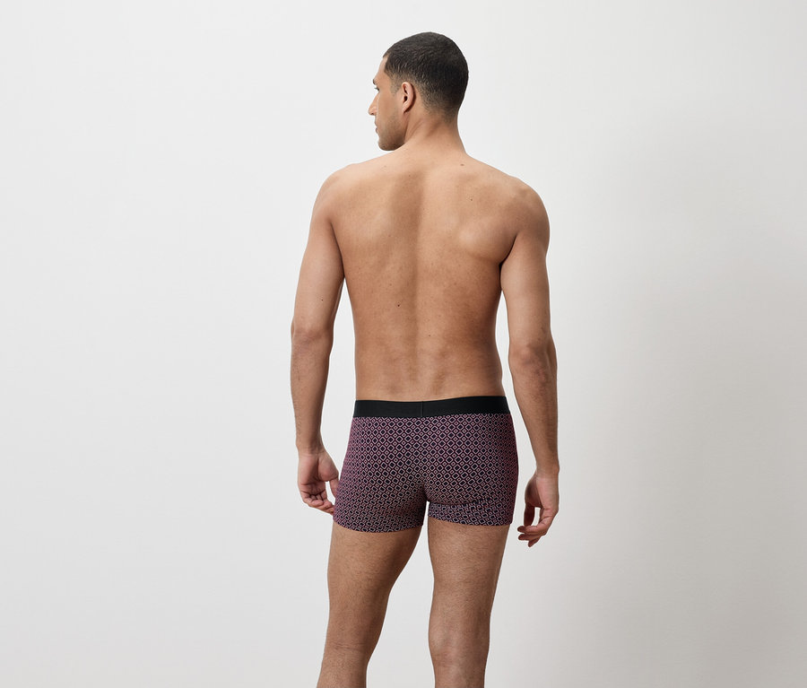 Homme de dos, portant un caleçon boxer violet avec un motif géométrique.