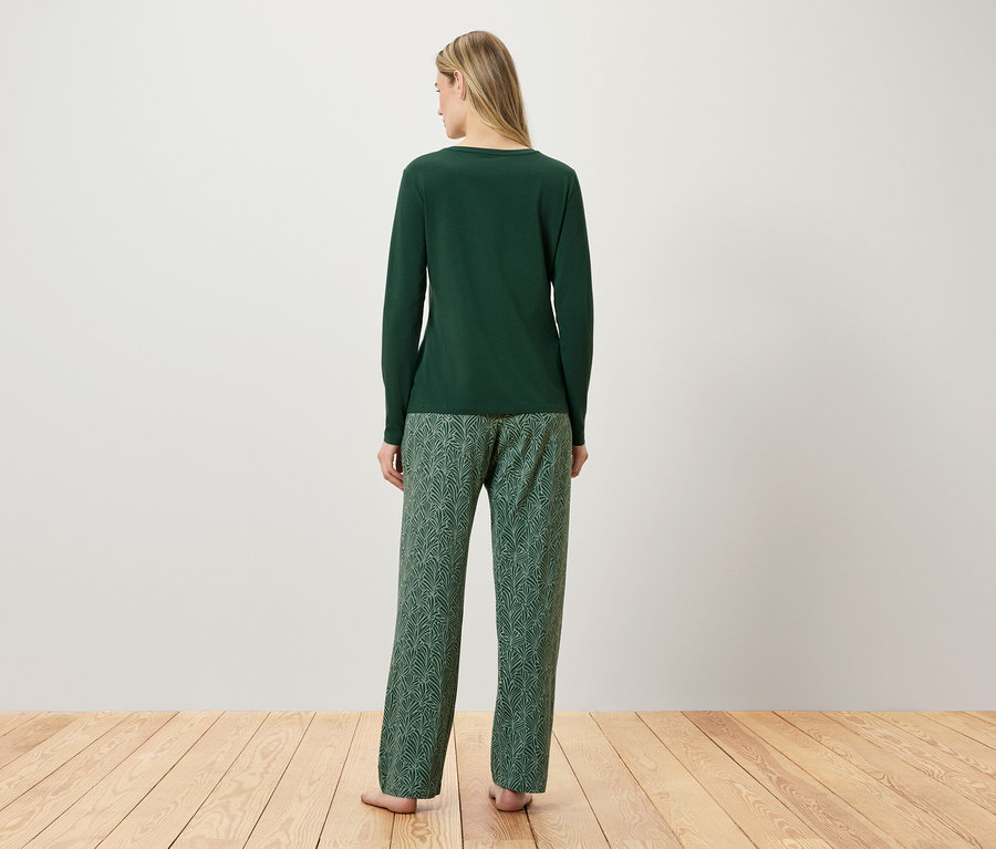 Une femme, vue de dos, porte un pyjama vert.