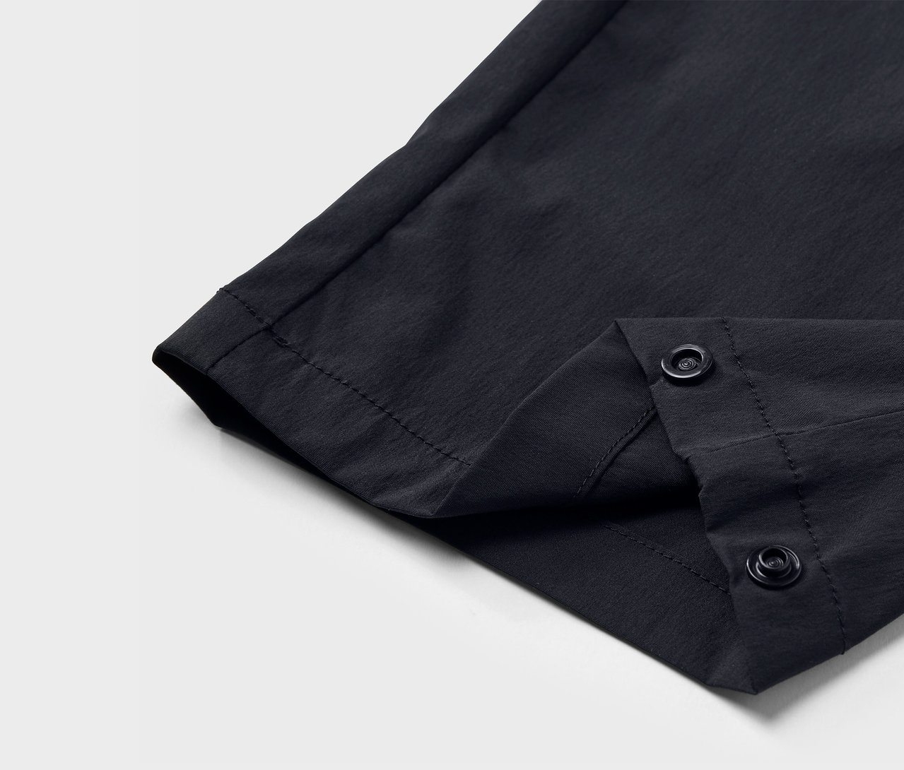 Gros plan sur un pantalon technique noir avec fermeture à boutons-pression.