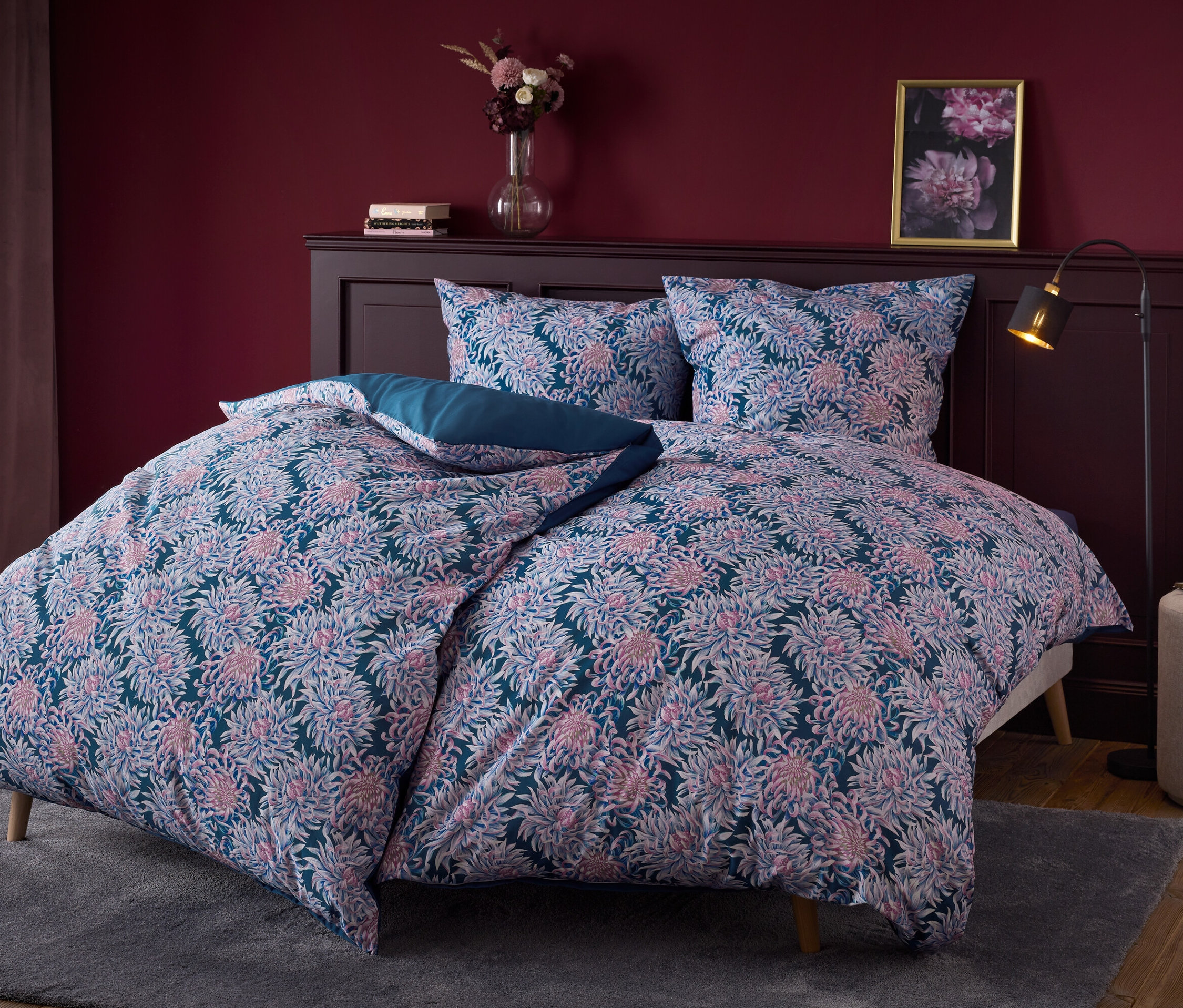 Linge de lit à fleurs sur un lit avec une tête de lit en bois foncé.