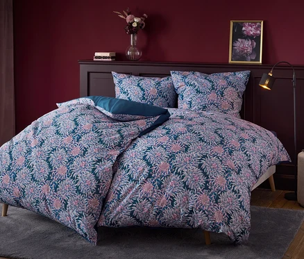Linge de lit à fleurs sur un lit avec une tête de lit en bois foncé.