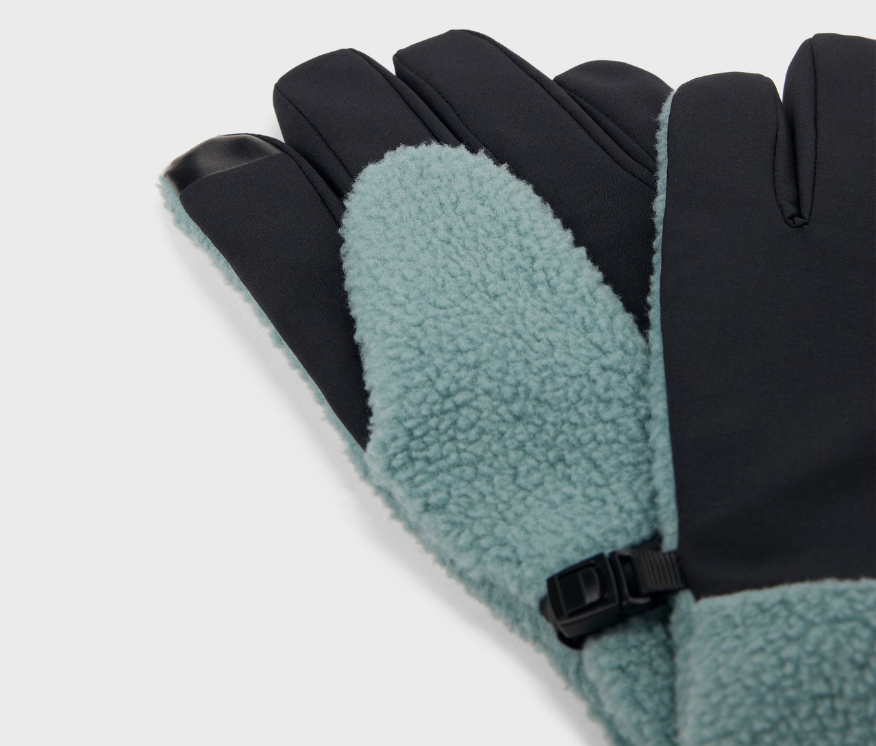 Gros plan de gants bleu-vert et noirs avec doublure en polaire et boucle noire.