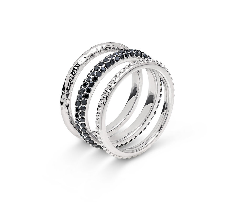 Gros plan d'une bague argentée à quatre rangs, dont un orné de pierres noires.