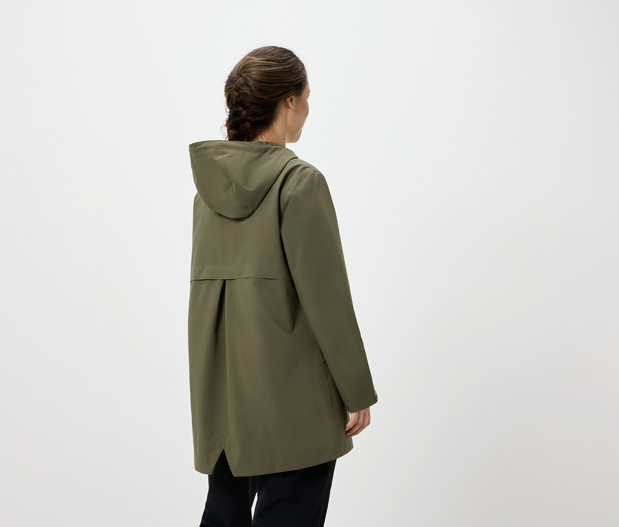 Une femme, vue de dos, porte un manteau à capuche vert olive et un pantalon noir.