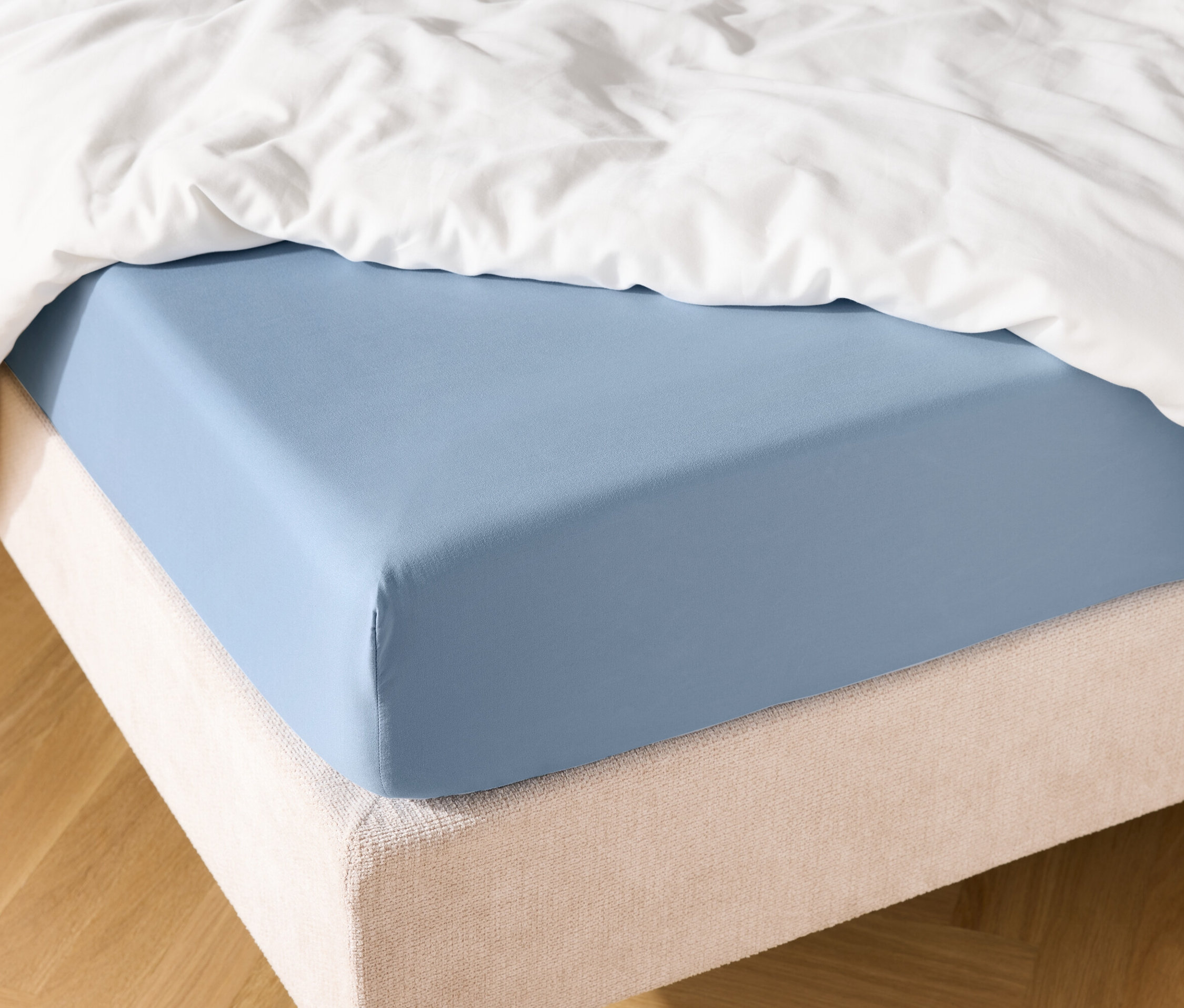 Drap-housse bleu clair sur un lit avec une couverture blanche.