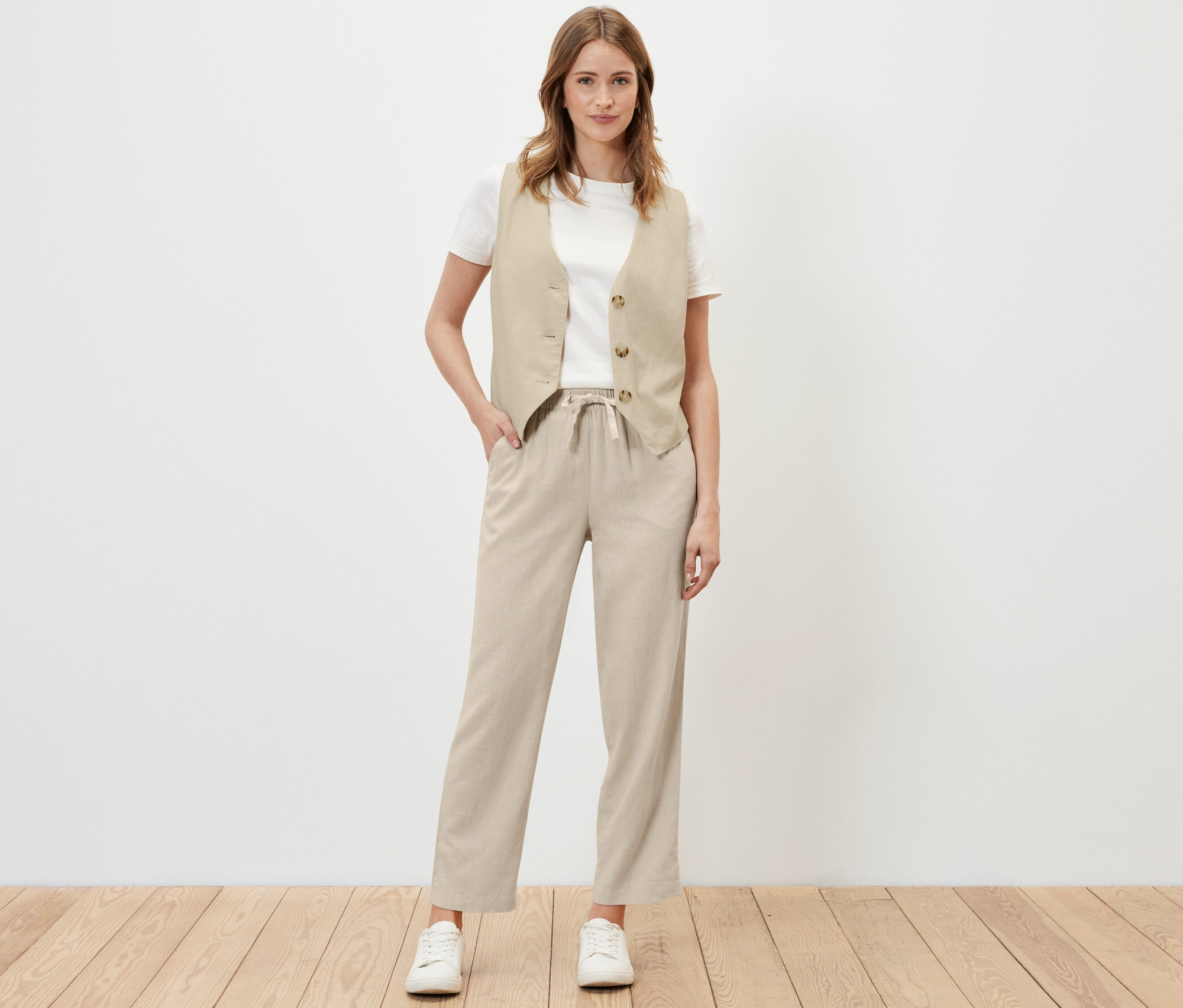 Femme posant en pantalon et gilet de lin couleur sable.